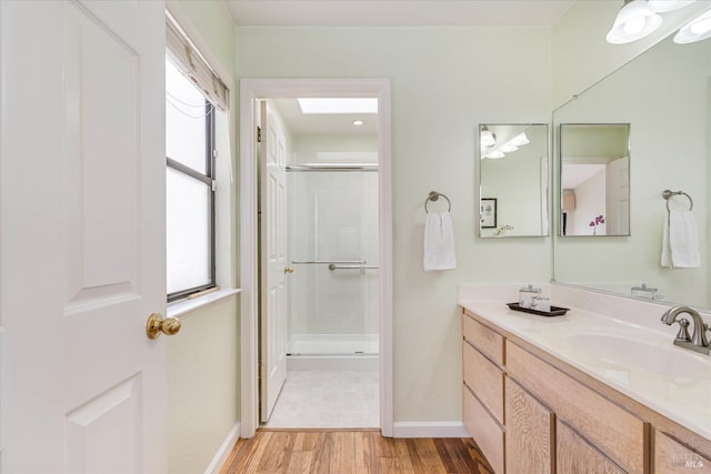 bathroom with a shower with shower door, wood finished floors, vanity, and baseboards