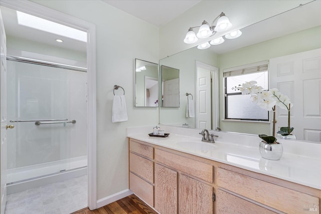 bathroom featuring a stall shower, vanity, and baseboards