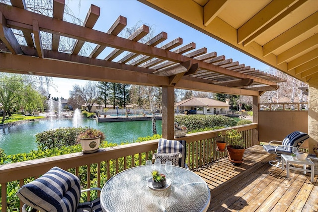 wooden terrace with a water view, a pergola, and outdoor dining space