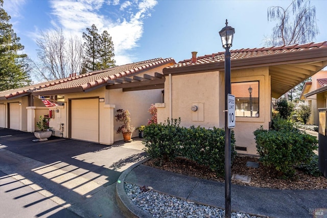 view of front facade featuring an attached garage, a tiled roof, and stucco siding