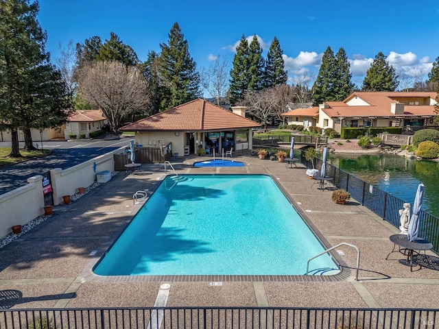 pool with a patio, a community hot tub, and fence