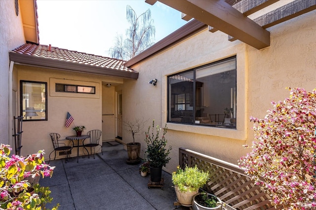 property entrance with a tile roof, a patio area, and stucco siding