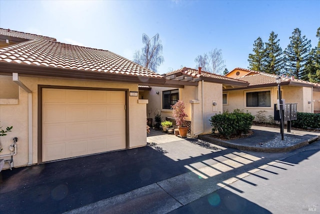 view of front of home featuring aphalt driveway, a tile roof, an attached garage, and stucco siding