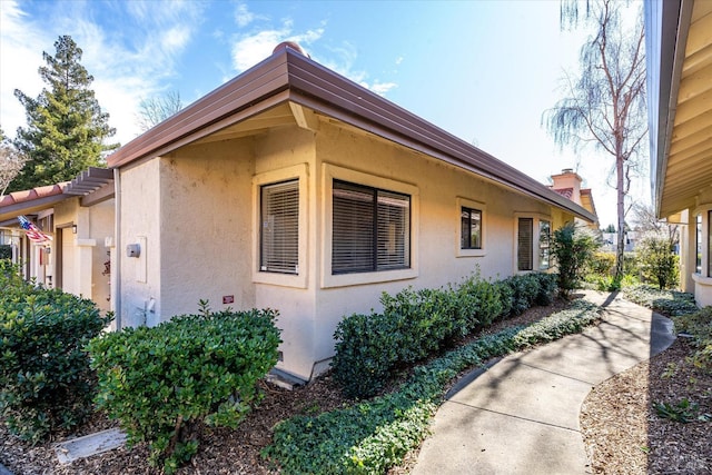 view of property exterior with a chimney and stucco siding