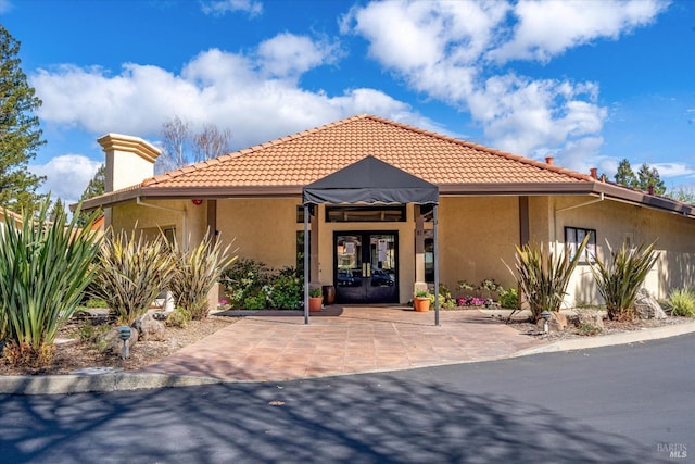 view of front of house featuring a tiled roof, french doors, and stucco siding