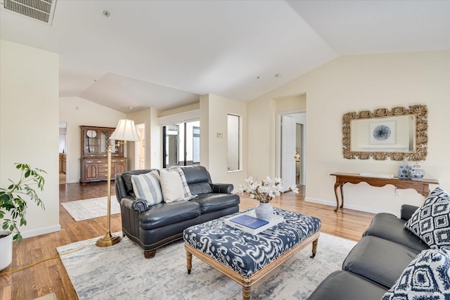 living room with vaulted ceiling, wood finished floors, visible vents, and baseboards