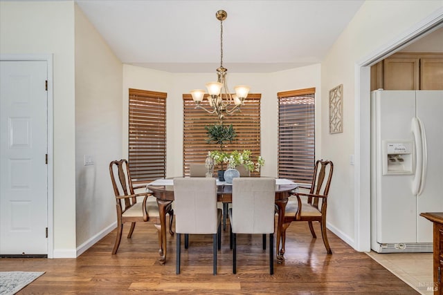 dining area with light wood finished floors, baseboards, and a notable chandelier