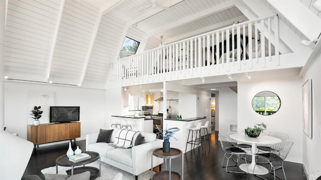 living area with a wealth of natural light, wood finished floors, beam ceiling, and baseboards