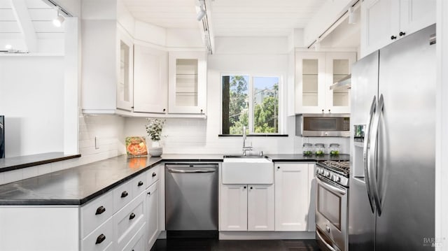 kitchen with appliances with stainless steel finishes, dark countertops, backsplash, and white cabinetry