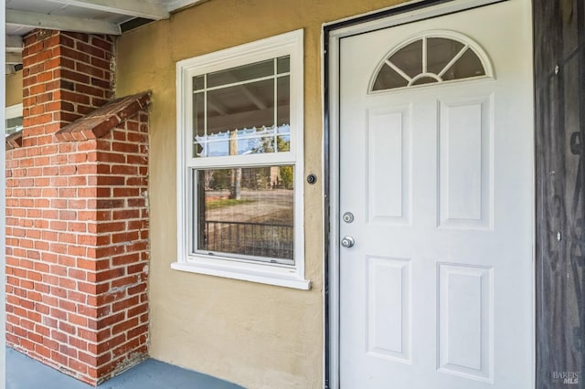 entrance to property featuring brick siding and stucco siding