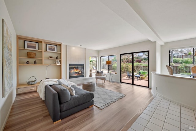 living room with light wood-type flooring, a tile fireplace, and baseboards