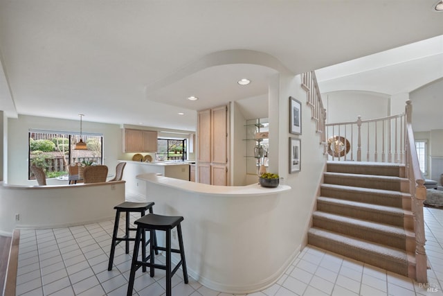 bar with light tile patterned floors, arched walkways, recessed lighting, baseboards, and stairway