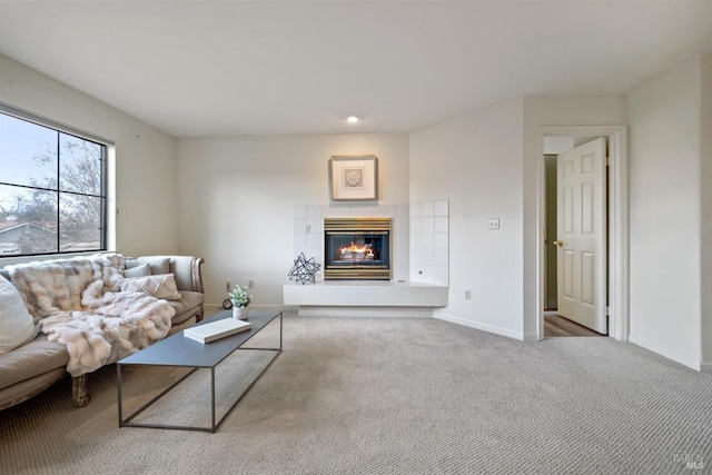 living room featuring carpet, a tile fireplace, and baseboards