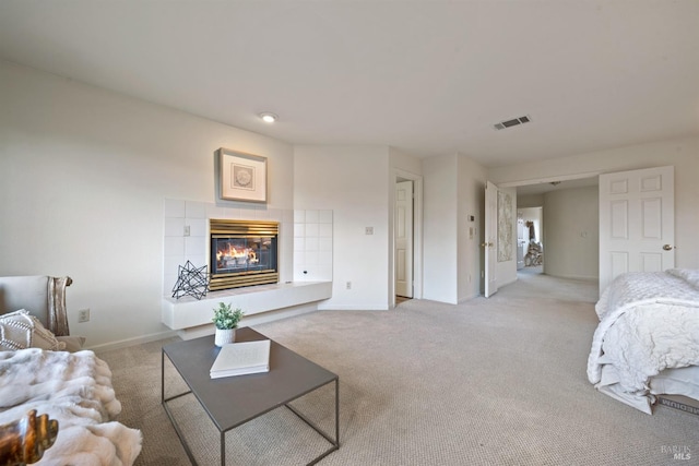 living room featuring baseboards, a fireplace, visible vents, and light colored carpet