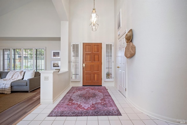 foyer with baseboards, high vaulted ceiling, and light tile patterned flooring