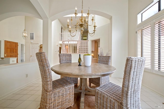 dining space with a chandelier, a towering ceiling, arched walkways, and visible vents