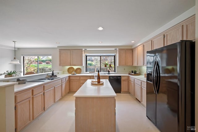 kitchen featuring black appliances, a center island, light countertops, and light brown cabinetry