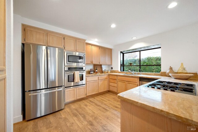 kitchen featuring recessed lighting, stainless steel appliances, a sink, light brown cabinetry, and light wood finished floors