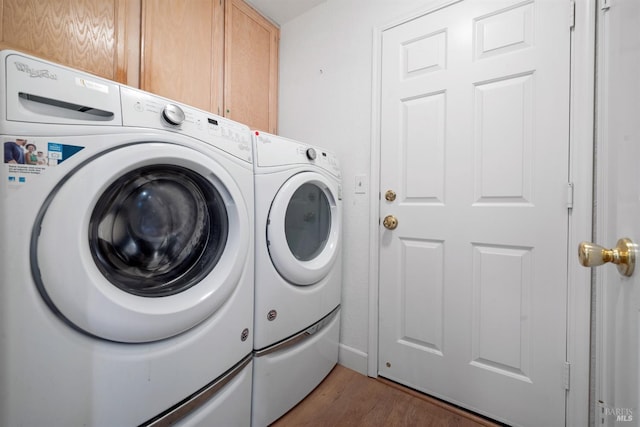 washroom with cabinet space, washer and dryer, and wood finished floors