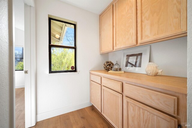 bar featuring light wood-style floors and baseboards