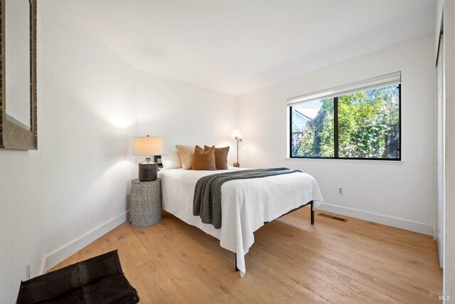 bedroom with light wood-style flooring, visible vents, and baseboards