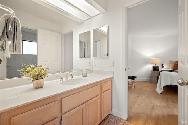 ensuite bathroom with baseboards, vanity, ensuite bath, and wood finished floors