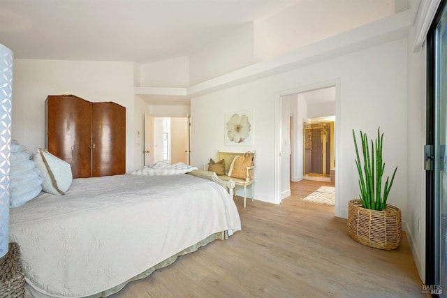 bedroom with lofted ceiling and light wood-style floors