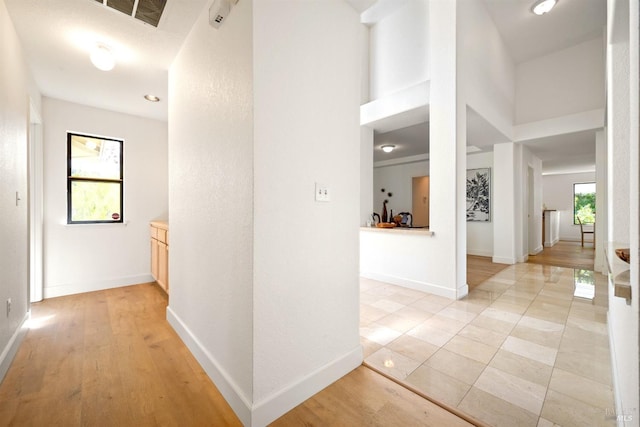 corridor with a healthy amount of sunlight, visible vents, and baseboards