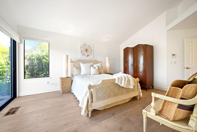 bedroom featuring lofted ceiling, light wood-type flooring, visible vents, and baseboards