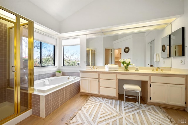 bathroom with a garden tub, double vanity, a stall shower, vaulted ceiling, and a sink