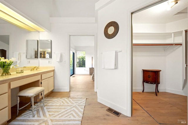 bathroom featuring baseboards, visible vents, wood finished floors, and vanity