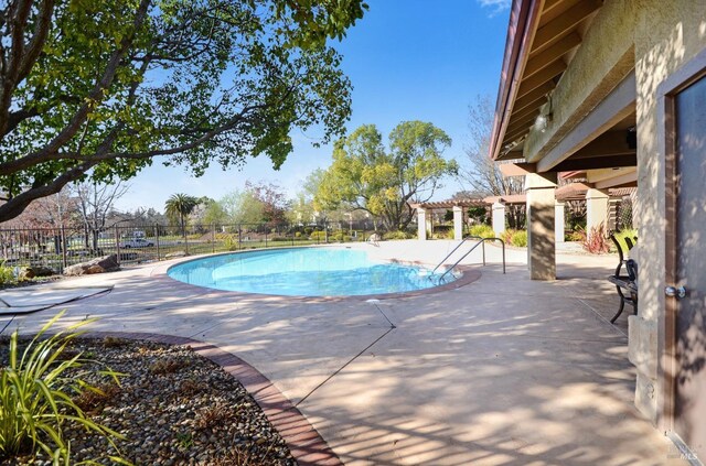 pool featuring fence, a pergola, and a patio