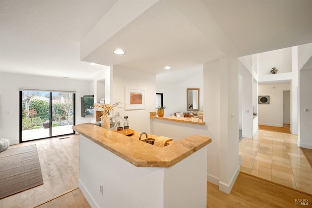 kitchen with open floor plan, a peninsula, light wood finished floors, and recessed lighting