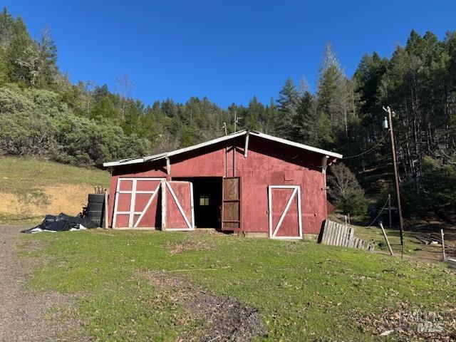 view of barn featuring a view of trees and a yard