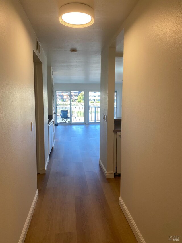 corridor featuring visible vents, baseboards, and dark wood-style flooring