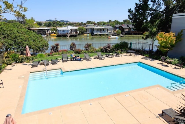 community pool featuring a patio area, fence, and a water view