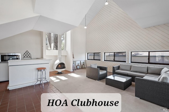 carpeted living area featuring high vaulted ceiling, a wood stove, and wooden walls