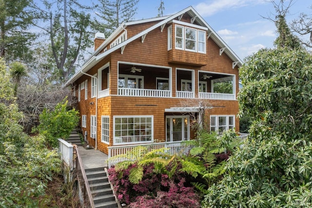 view of front of property featuring a balcony, stairs, a chimney, and a ceiling fan