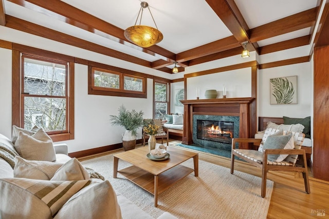 living room with beam ceiling, a premium fireplace, light wood-type flooring, and a wealth of natural light