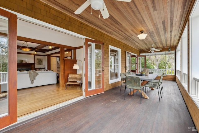 unfurnished sunroom with a ceiling fan, wooden ceiling, and beamed ceiling