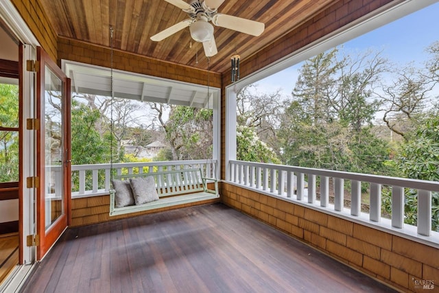 unfurnished sunroom with wood ceiling, plenty of natural light, and a ceiling fan