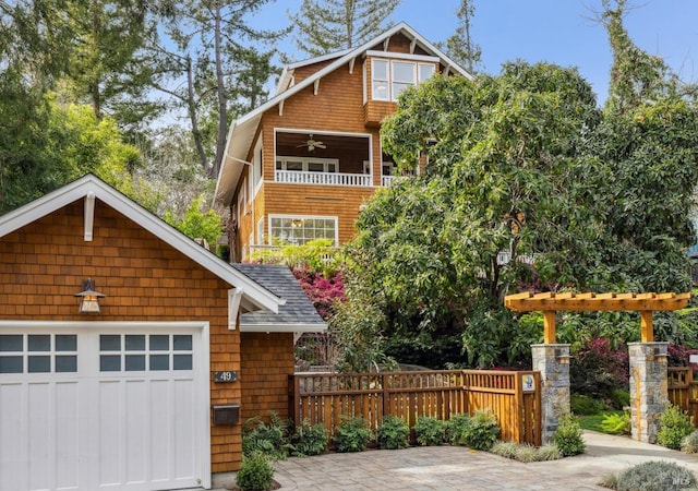 view of front of home featuring ceiling fan, roof with shingles, fence, and a balcony