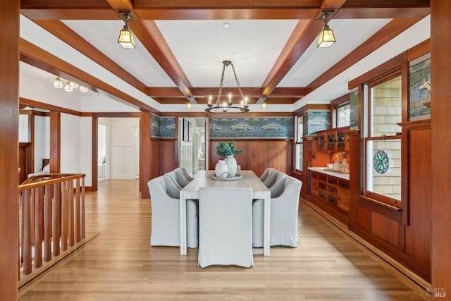 dining area with a chandelier, beamed ceiling, and light wood-style flooring