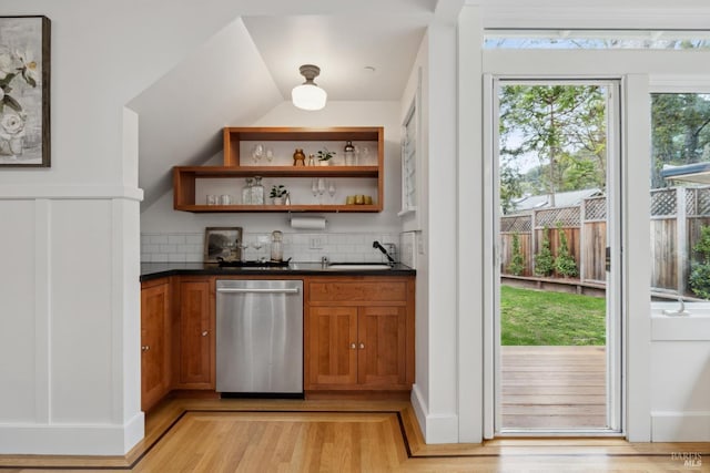 bar with tasteful backsplash, lofted ceiling, stainless steel dishwasher, light wood-style floors, and a sink