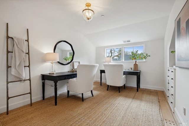 office space featuring baseboards, visible vents, and vaulted ceiling