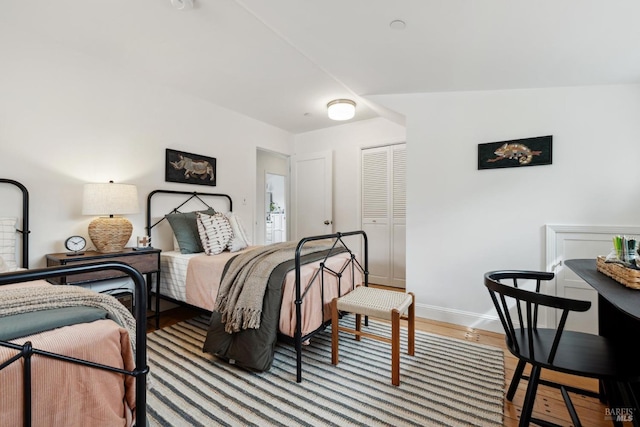 bedroom with a closet, wood finished floors, and baseboards