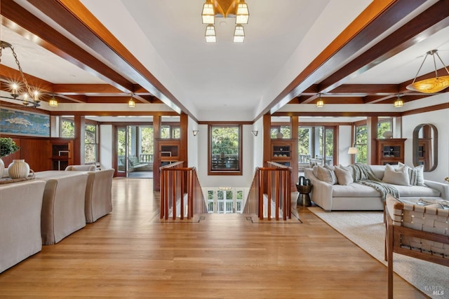 living area with a healthy amount of sunlight, beamed ceiling, and light wood finished floors