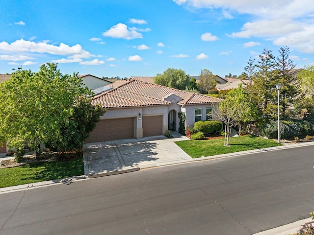 mediterranean / spanish home featuring concrete driveway, a tiled roof, an attached garage, a front yard, and stucco siding