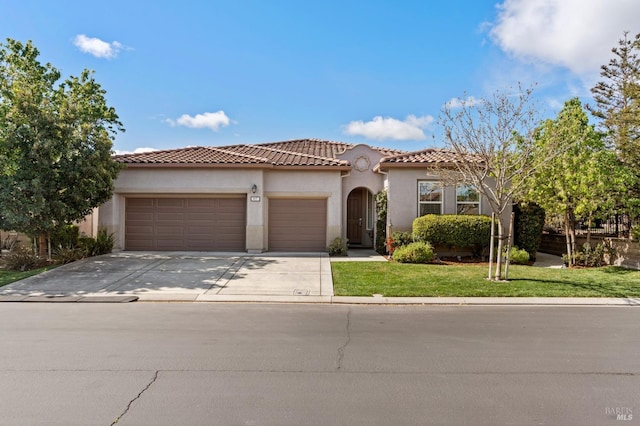 mediterranean / spanish-style house featuring a garage, a tiled roof, driveway, stucco siding, and a front lawn