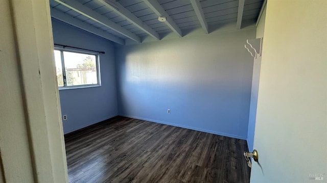 empty room with baseboards, beam ceiling, and wood finished floors